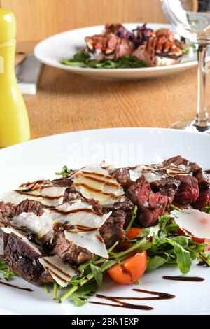 Plat principal italien traditionnel. Tagliata de boeuf : oeil de côte de boeuf tendre, arugula, tomates cerises, copeaux de Grana Padano, réduction balsamique. Emilie-Romagne Banque D'Images