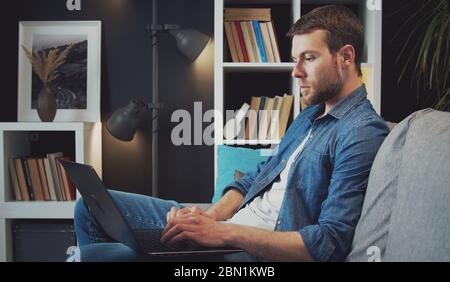 Homme utilisant un ordinateur portable canapé Banque D'Images