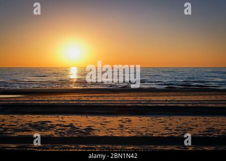 Magnifique coucher de soleil au nord sur la mer Baltique à Klaipeda, Lituanie. Soleil bas au-dessus de la mer calme, sentiers sur le sable. Concept de calme, de calme contemplation. Banque D'Images