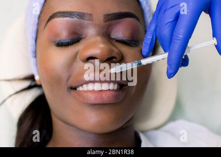 Cropped shot of young african american woman getting injection en beauté lèvres isolated on white Banque D'Images