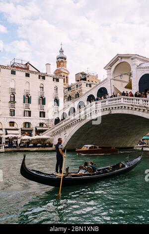 Venise, Italie - 04 octobre 2019 : les touristes nagent sous le pont sur une gondole. Le magnifique pont Ponte di Rialto au-dessus du Grand Canal central Banque D'Images