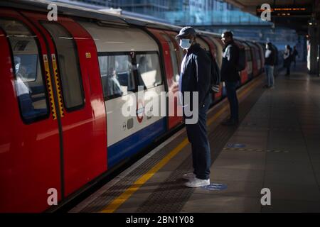 Les passagers portent un masque facial et se tiennent à l'écart sur une plate-forme à la station de métro Canning Town de Londres. Banque D'Images