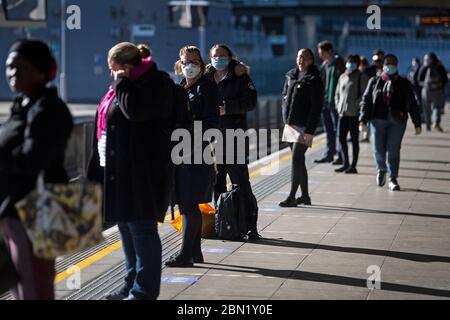 Les passagers portent un masque facial et se tiennent à l'écart sur une plate-forme à la station de métro Canning Town de Londres. Banque D'Images