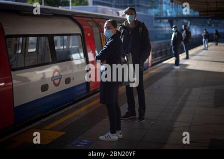 Les passagers portent un masque facial et se tiennent à l'écart sur une plate-forme à la station de métro Canning Town de Londres. Banque D'Images