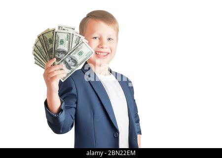 Mignon petit garçon caucasien tient un ventilateur d'un paquet de billets de cent dollars, souriant et regardant la caméra isolée sur un fond blanc avec copie spac Banque D'Images