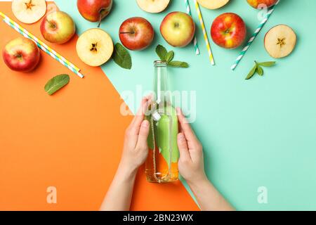 Les mains des femmes tiennent une bouteille de cidre sur fond deux tons. Composition avec cidre Banque D'Images