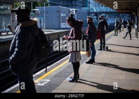 Les passagers portent un masque facial et se tiennent à l'écart sur une plate-forme à la station de métro Canning Town de Londres. Banque D'Images