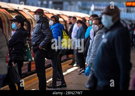 Passagers portant un masque facial sur une plate-forme à la station de métro Canning Town de Londres. Banque D'Images