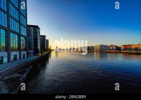 7 avril 2020, Berlin, la vue de la Spree en soirée avec le soleil couchant. Sur la gauche sur la photo le complexe de TrepwTowers (architecte Gerhard Spangenberg). La molécule de sculpture en aluminium Man de Jonathan Borofsky. | utilisation dans le monde entier Banque D'Images