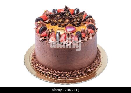 Gâteau au chocolat décoré de crème, fraises, biscuits sur une assiette dorée, un plateau gros plan. Banque D'Images