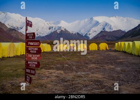 Signes avec des villes en russe et la distance à eux. Camp de tente. Sommets enneigés. Style de vie. Banque D'Images