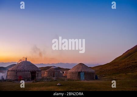 Établissement traditionnel nomade en Asie centrale. Tapis de feutre yourts. Paysage pittoresque. Coucher de soleil sur un terrain montagneux. Banque D'Images