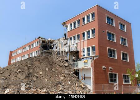 Un bâtiment partiellement démoli. Une grande partie du centre du bâtiment est manquante, et il y a une grosse pile de terre devant. Beaucoup de débris et de pendaison Banque D'Images