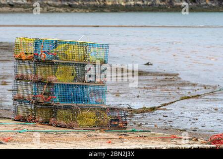 Une pile de pièges à homard sur une petite barge en bois sur une plage à marée basse. Il y a neuf pièges dans la pile, ils ont des roches à l'intérieur pour le poids. Banque D'Images