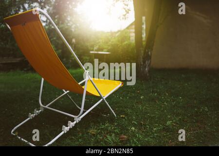 Chaise en tissu jaune vide dans le jardin d'été, concept reposant et relaxant, personne Banque D'Images