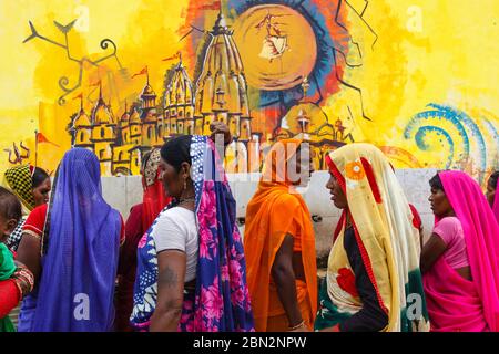 Orcha, Madhya Pradesh, Inde : UN groupe de femmes vêtues de saris colorés s'arroge d'une fontaine à l'extérieur du temple RAM Raja. Murale représentant Chatu Banque D'Images