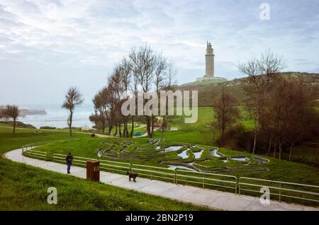 A Coruna, Galice, Espagne - 10 février 2020 : UN homme marche son chien dans un parc public sous la Tour d'Hercule, ancien phare romain. Intégré à la Banque D'Images