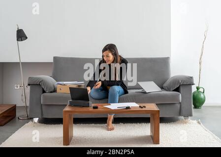 Jeune femme travaillant à la maison et ayant une vidéoconférence d'affaires à sa maison Banque D'Images