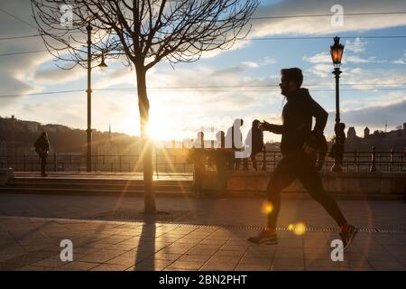 Homme courant dans la ville contre le coucher du soleil. Banque D'Images