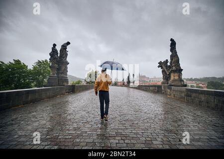 Homme solitaire avec parapluie dans la pluie lourde marchant sur le pont vide Charles. Prague République tchèque Banque D'Images