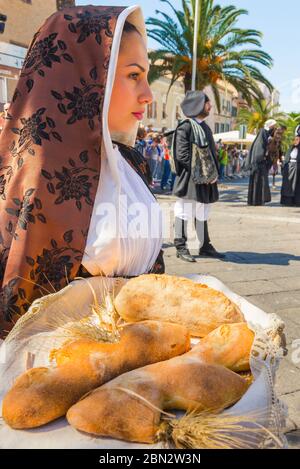 La cuisine de Sardaigne, une jeune femme en robe traditionnelle sarde porte un panier de pain pendant le festival de Cavalcata à Sassari, Sardaigne. Banque D'Images