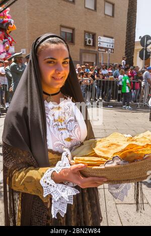 Fête de la Sardaigne, une jeune femme vêtue de Sardaigne porte un panier de pain traditionnel - panneau carasau - pendant le festival de Cavalcata à Sassari Banque D'Images