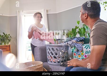 Couple d'âge mûr parlant et linge pliant dans le salon Banque D'Images