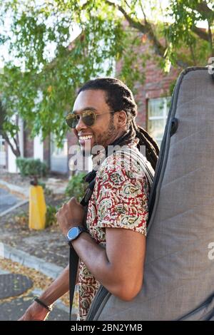 Portrait souriant musicien masculin portant de la guitare dans la rue Banque D'Images