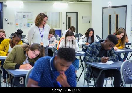 Enseignant du secondaire supervisant les élèves qui se font passer un examen aux bureaux Banque D'Images