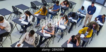 Instructeur supervisant les élèves du secondaire qui se font passer l'examen aux bureaux Banque D'Images