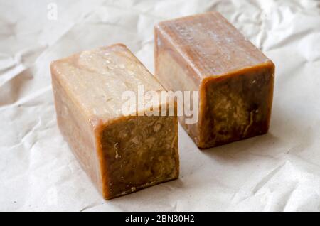 Grandes pièces rectangulaires dans un gros plan naturel. Deux barres brunes de savon écologique sur papier brun. Produits de soins personnels naturels. Mise au point sélective. Banque D'Images