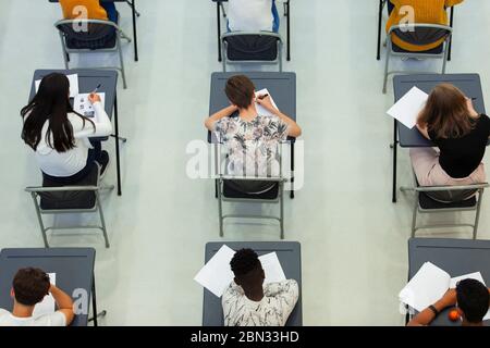 Vue du dessus des élèves du secondaire qui se font passer un examen aux bureaux de la salle de classe Banque D'Images