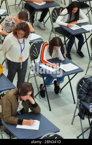 Enseignant du secondaire supervisant les élèves qui se font passer un examen aux bureaux Banque D'Images