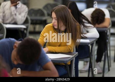 Jeune fille d'école secondaire ciblée prenant l'examen à bureau en classe Banque D'Images