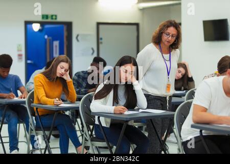 Enseignant du secondaire supervisant les élèves qui se font passer un examen aux bureaux Banque D'Images