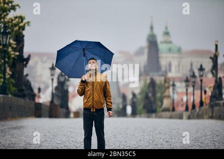 Homme solitaire avec parapluie dans la pluie lourde sur le pont vide Charles. Prague République tchèque Banque D'Images