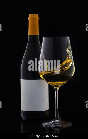 Bouteille de vin blanc et verre de vin avec étiquette vierge isolée sur fond noir. Banque D'Images