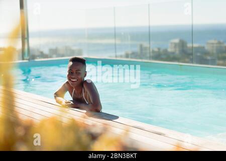 Bonne jeune femme dans la piscine ensoleillée de luxe Banque D'Images