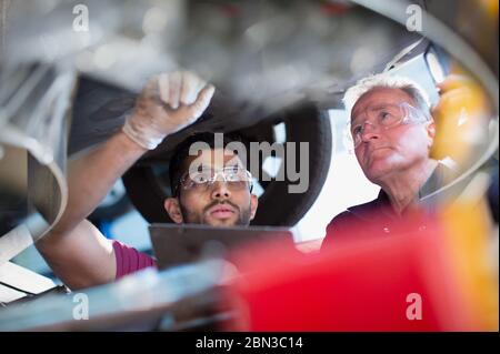 Mécanique masculine travaillant sous voiture dans l'atelier de réparation automobile Banque D'Images