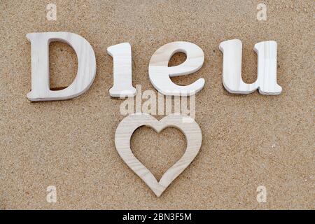 Lettres en bois formant le mot Dieu ( dieu ) avec coeur sur fond de sable de plage. Symbole chrétien. Banque D'Images