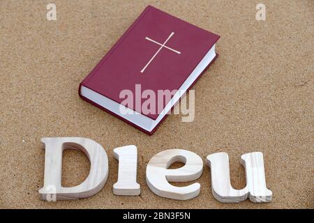 Lettres en bois formant le mot Dieu avec la Bible sur fond de sable de plage. Symbole chrétien. Banque D'Images