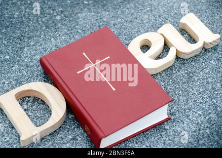 Lettres en bois formant le mot Dieu avec la Bible sur fond de marbre noir. Symbole chrétien. Banque D'Images