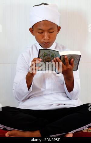 Mosquée Masjid AR-Rohmah. Un garçon musulman lisant un Coran arabe. Chau Doc. Vietnam. Banque D'Images