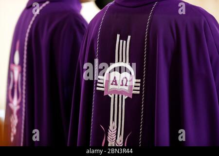 Prêtres portant un chasuble romain violet avec broderie Alpha et Omega. Quy Nhon. Vietnam. Banque D'Images
