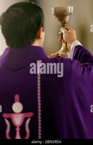 Masse catholique. Prêtre portant un chasuble romain violet. Célébration eucharistique. Altitude. Quy Nhon. Vietnam. Banque D'Images