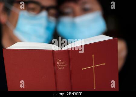 Homme et femme lisant la bible avec un masque jetable pour éviter le coronavirus contagieux ( COVID-19). France. Banque D'Images
