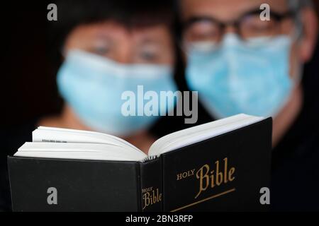 Homme et femme lisant la bible avec un masque jetable pour éviter le coronavirus contagieux ( COVID-19). France. Banque D'Images