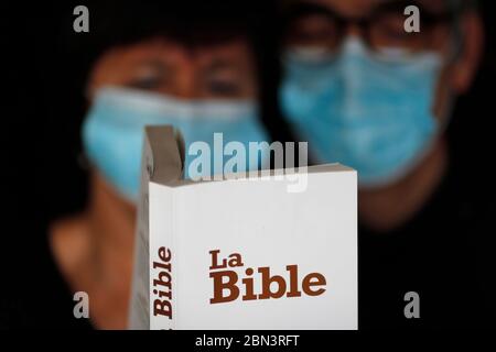 Homme et femme lisant la bible avec un masque jetable pour éviter le coronavirus contagieux ( COVID-19). France. Banque D'Images