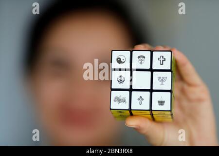 Femme avec un cube de Rubik avec des symboles religieux. Concept de dialogue interreligieux et interreligieux. Banque D'Images