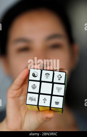 Femme avec un cube de Rubik avec des symboles religieux. Concept de dialogue interreligieux et interreligieux. Banque D'Images